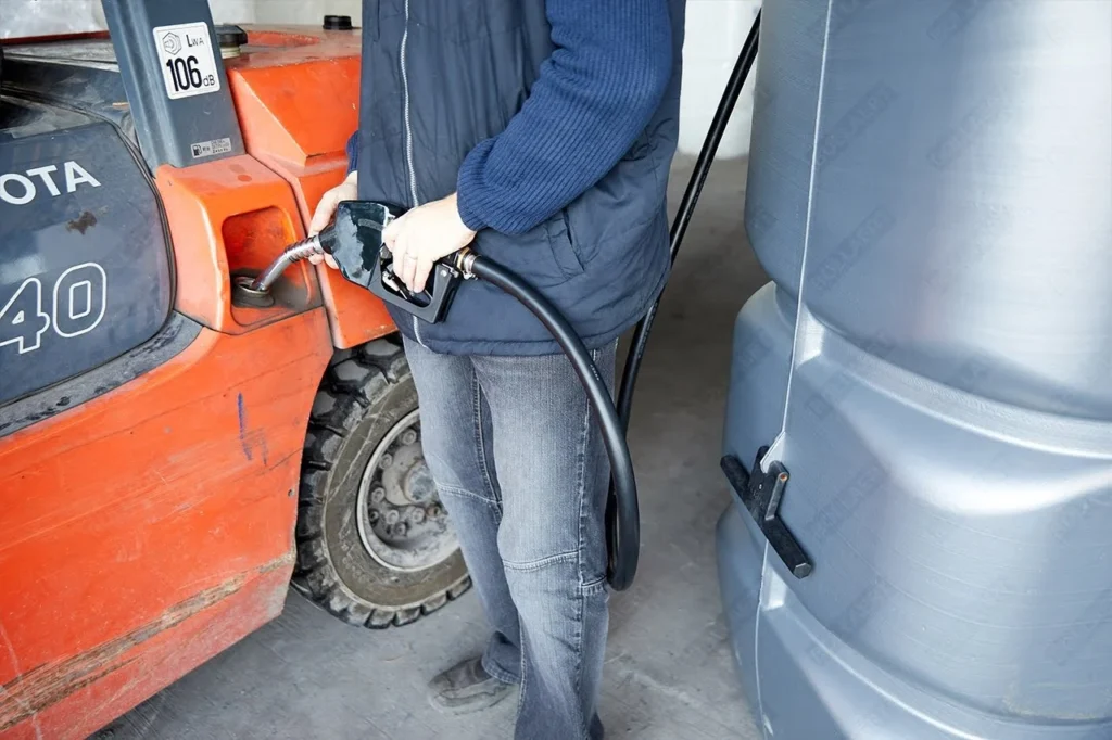 Een persoon die een heftruck bijvult met diesel via een compacte kunststof dieseltank met geïntegreerde pomp.