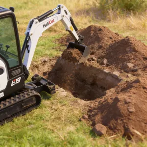 Septische put plaatsen. Stap 2 (Optie A): Een diepe put uitgraven voor de septische tank met behulp van een witte mini-graver in een tuin.